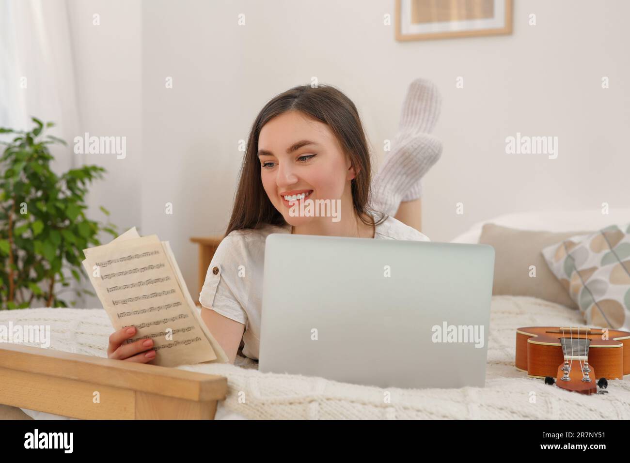 Donna che impara a giocare ukulele con corso di musica online a casa. Tempo per hobby Foto Stock