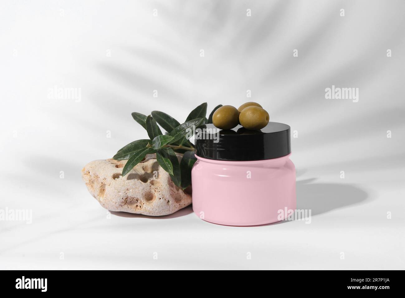 Vasetto di crema naturale, pietra e olive su fondo bianco. Prodotti cosmetici Foto Stock