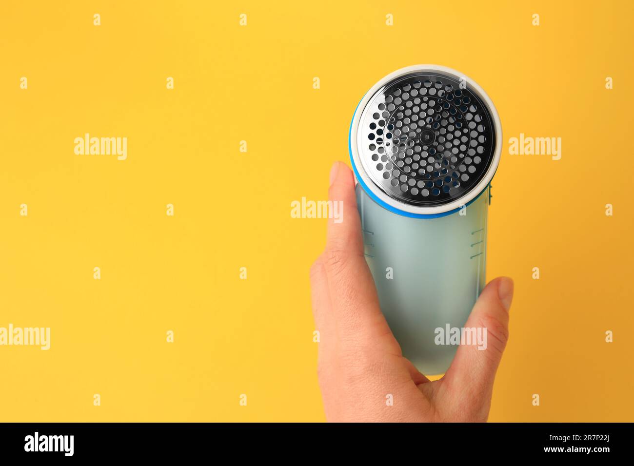 Donna che tiene un rasoio moderno su sfondo giallo, primo piano. Spazio per il testo Foto Stock