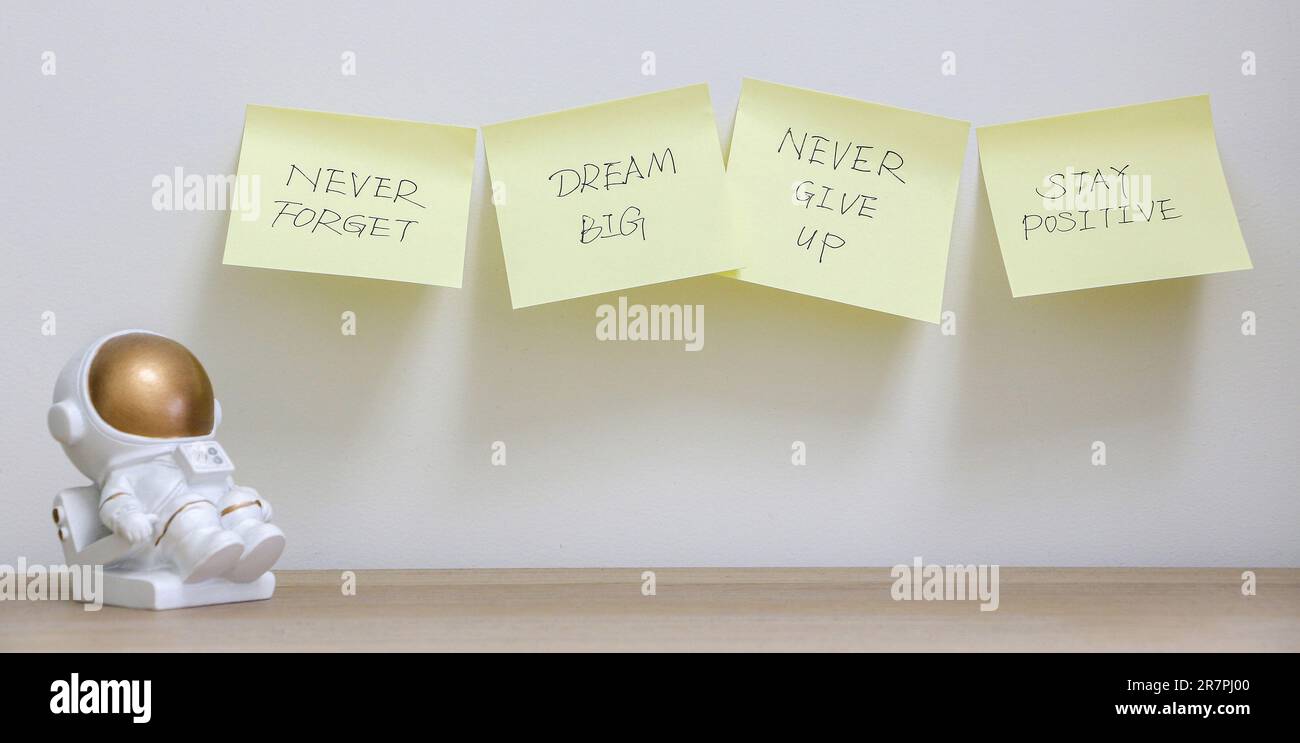 Concetto di ispirazione, quattro appunti gialli attaccati al muro con messaggi motivazionali per non dimenticare mai di sognare in grande, non rinunciare mai e rimanere positi Foto Stock