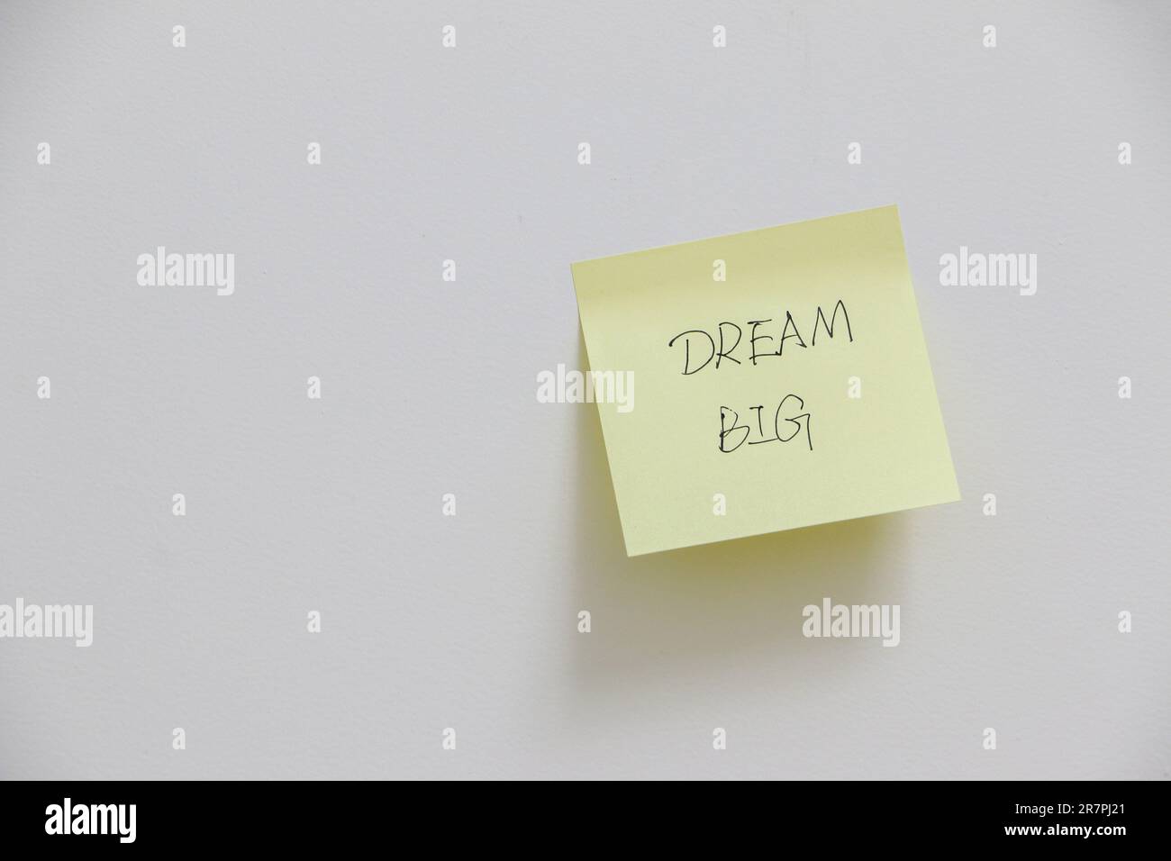 Messaggio motivazionale e stimolante per sognare in grande su note adesive gialle su pareti bianche, concetto di ambizione per il lavoro e la vita Foto Stock