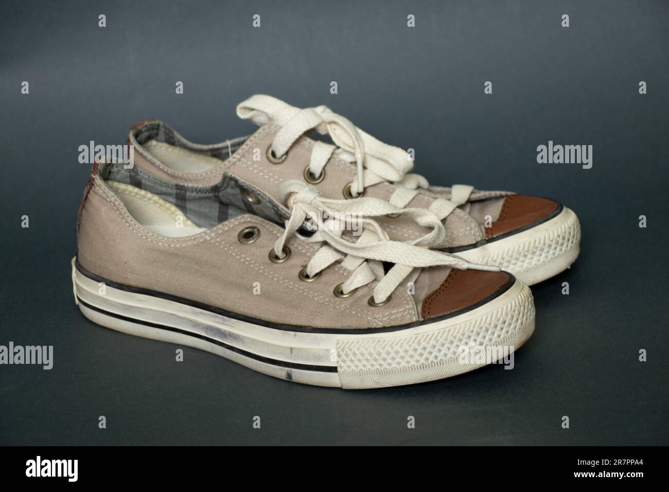 vecchie sneaker in tessuto chiaro su sfondo blu scuro Foto Stock