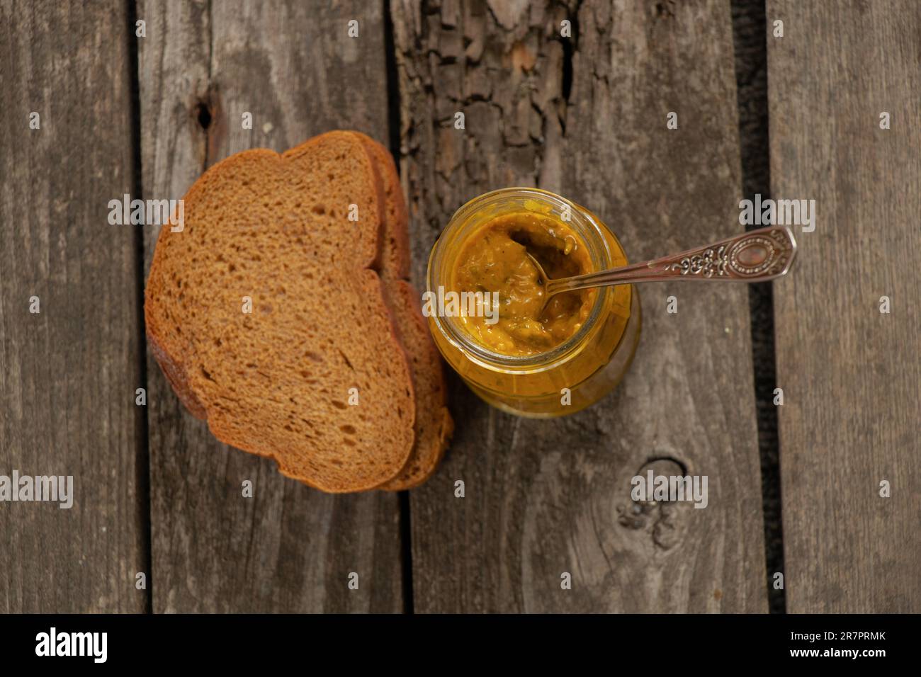 salsa di senape in un vaso di vetro e accanto a un pezzo di pane Foto Stock