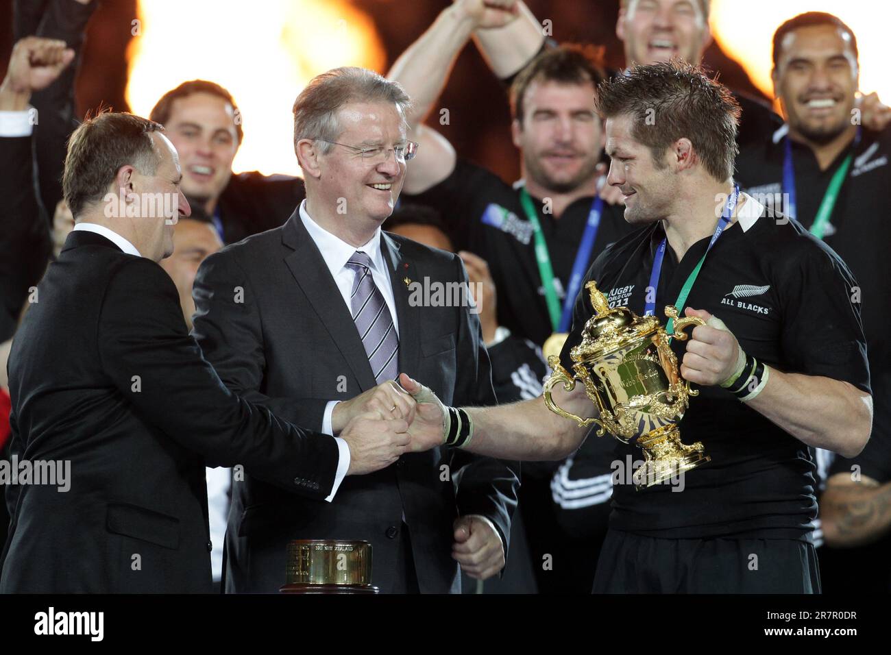 Il primo ministro John Key si scrolla le mani con il capitano neozelandese Richie McCaw mentre riceve la coppa dal presidente dell'IRB Bernard Lapasset dopo aver sconfitto la Francia nella finale di Rugby World Cup a Eden Park, Auckland, Nuova Zelanda, domenica 23 ottobre. 2011. Foto Stock