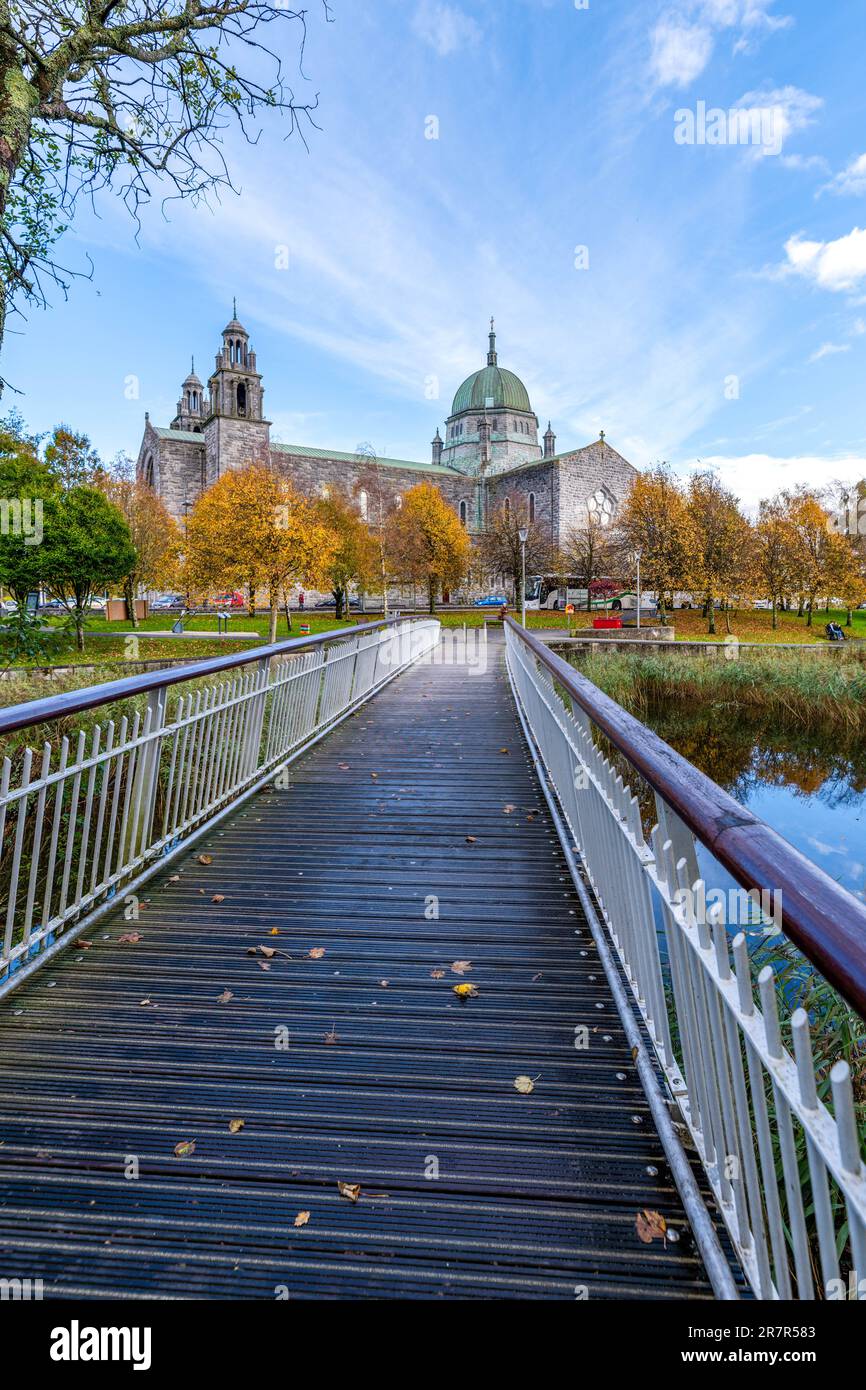 Una scena idilliaca di un fiume tranquillo con un piccolo ponte che conduce ad una chiesa con un caratteristico tetto a campanile Foto Stock
