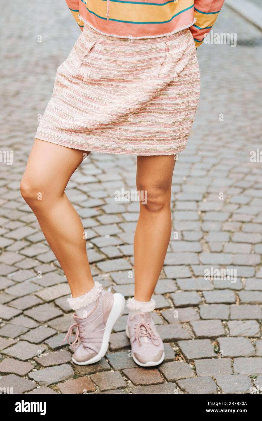 Belle gambe donna indossando sneakers moda e gonna corta rosa Foto Stock