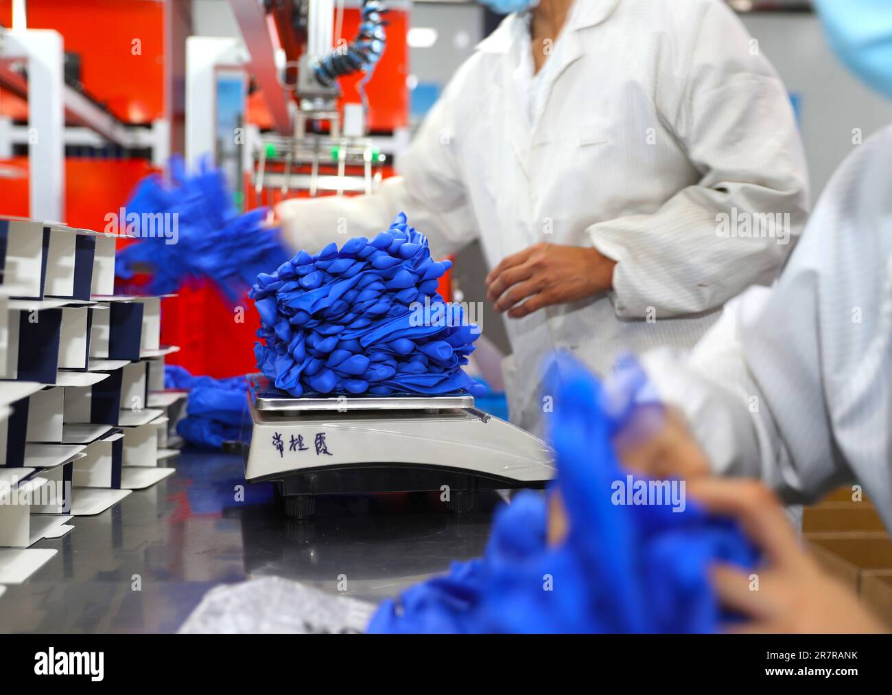 Un lavoratore lavora sulla linea di produzione di un produttore di guanti di protezione del lavoro nella città di Weifang, provincia di Shandong, Cina, 17 giugno 2023. Foto Stock