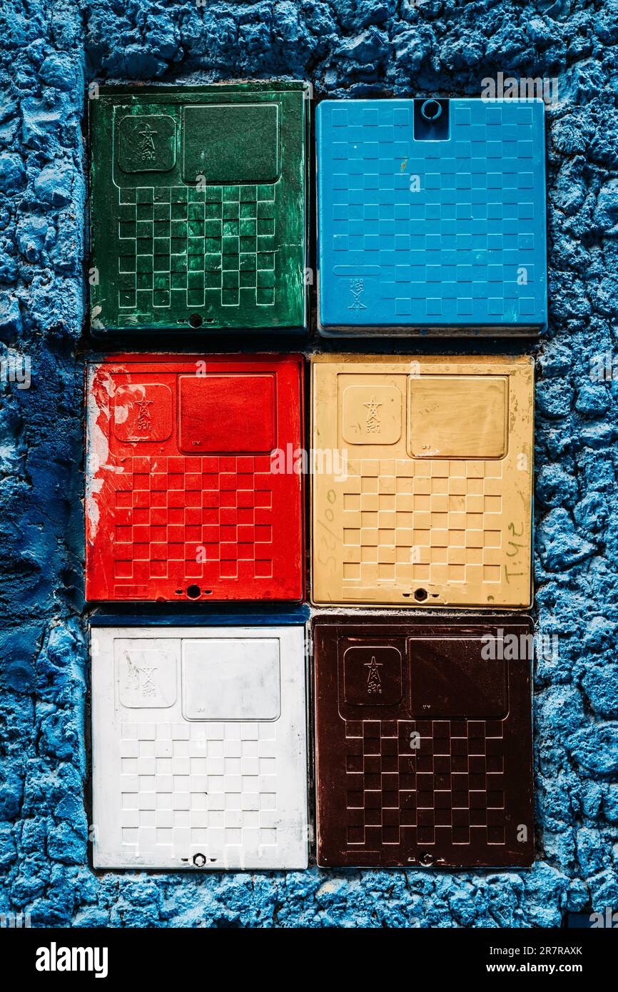 Scatole multicolore su parete blu: Una vivace fusione di colori, queste scatole vivaci aggiungono un tocco divertente all'accattivante sfondo blu. Foto Stock