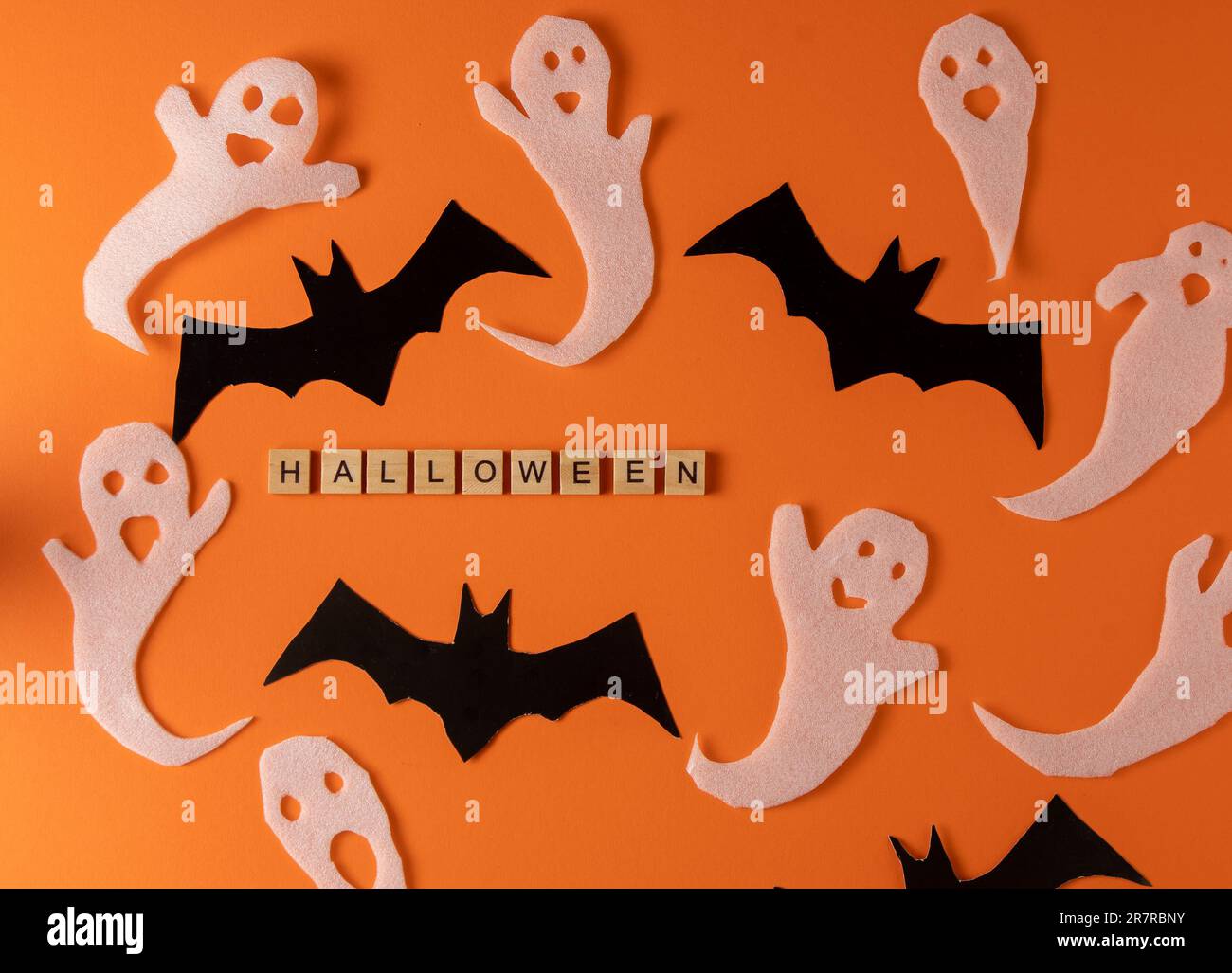 Fantasmi bianchi e mazza per la festa di Halloween. Immagine fantasma della carta di avvolgimento su sfondo arancione vista dall'alto. Fumetto Creepy Whisper. Fai-da-te fatto a mano. Impostare i caratteri boo. Parola frase di legno della lettera. Foto Stock