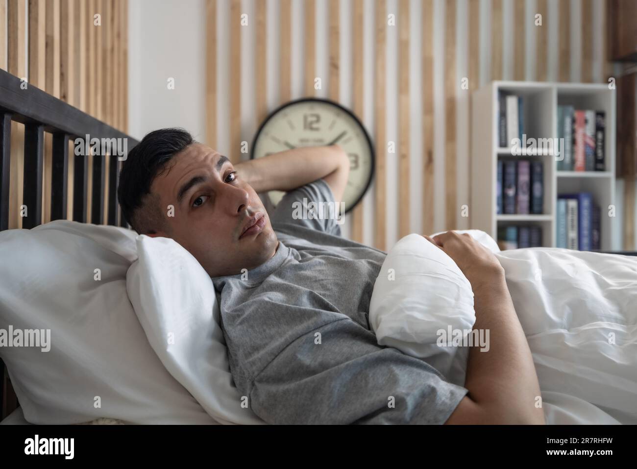 Pigro uomo oversleep, svegliarsi tardi, colpire la sveglia frequentemente con follia. Gli stili di vita moderni spesso richiedono che le persone lavorino sodo e mettano in straordinari Foto Stock