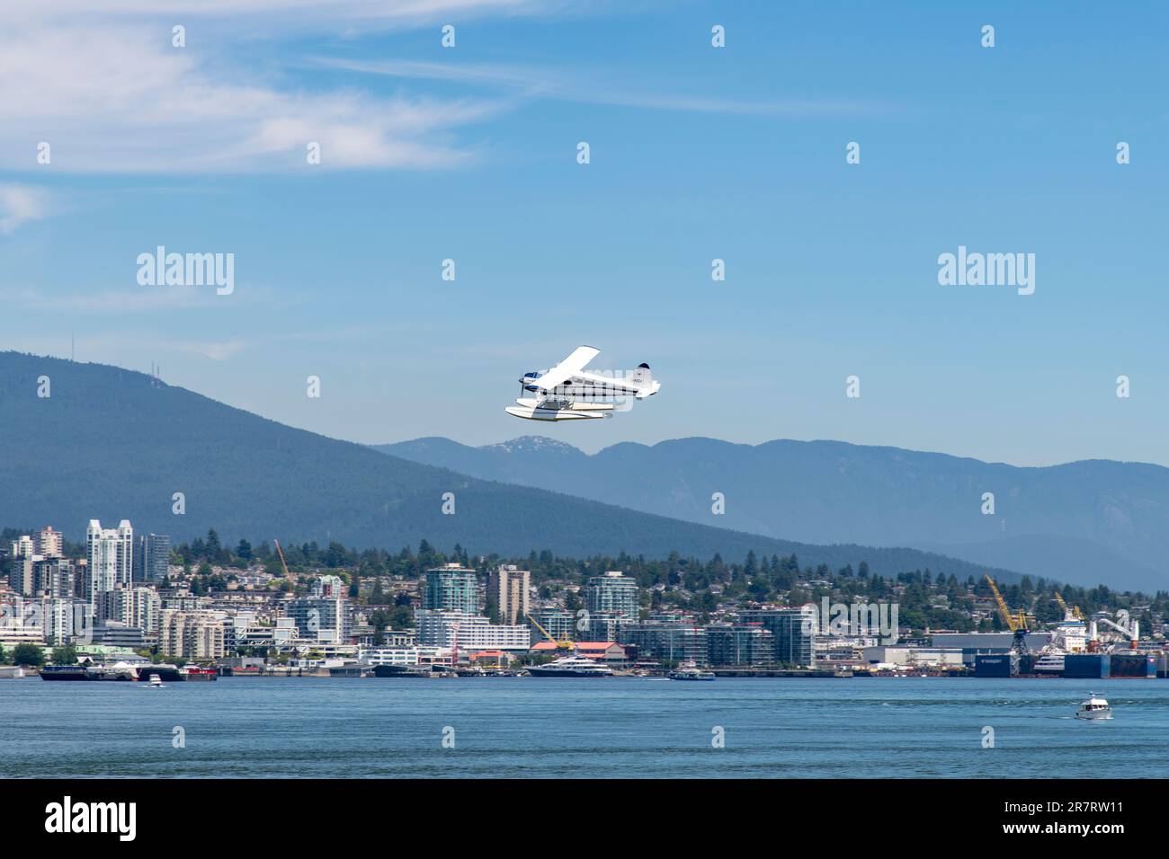 Vancouver, BC, Canada-Luglio 2022; Vista ravvicinata di un idrovolante o di un idrovolante appena sopra l'acqua del porto di Vancouver con area residenziale e Nord Sud Foto Stock