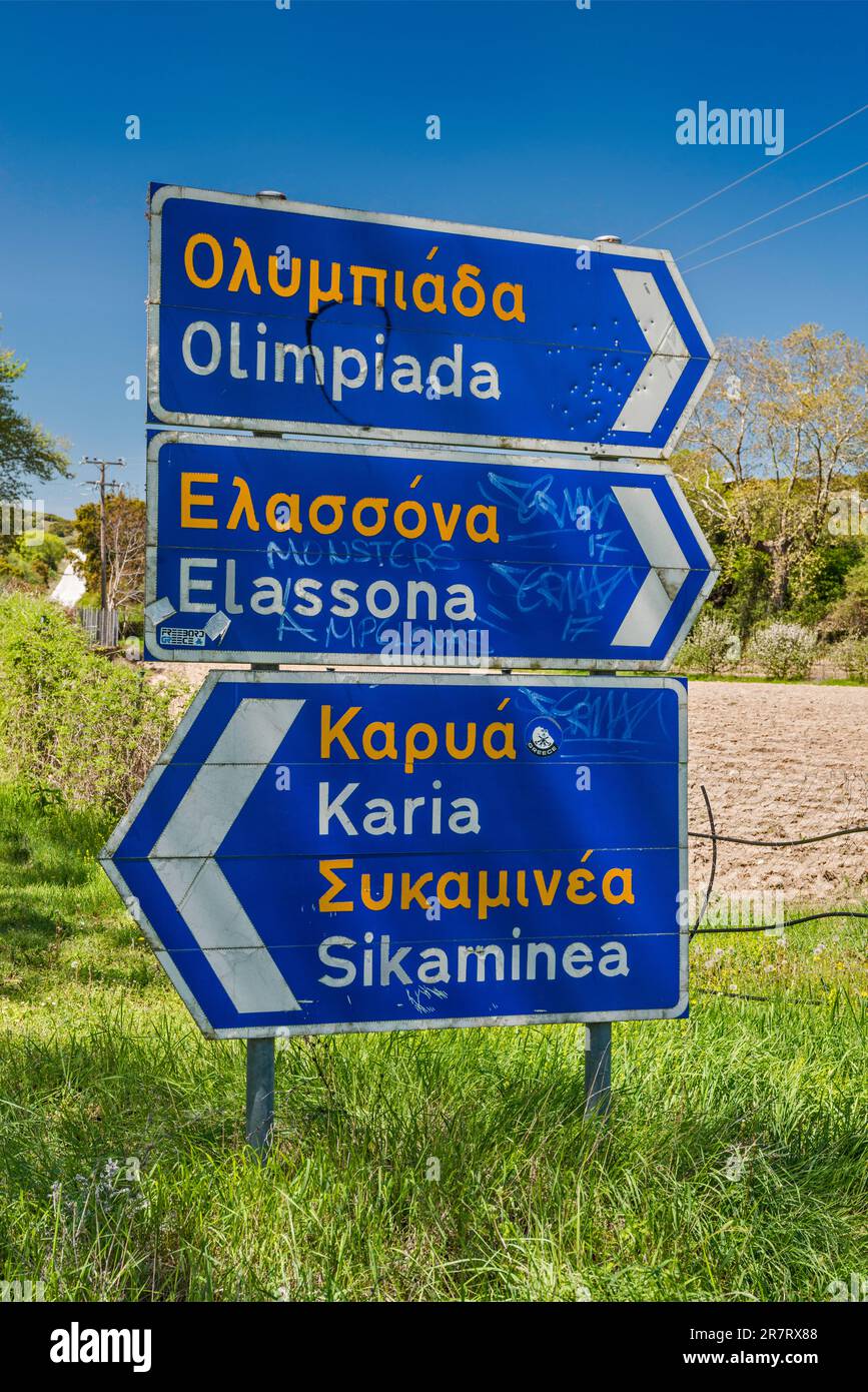 Indicazioni stradali, in alfabeto greco e romanizzato (traslitterato), zona del Monte Olimpo, vicino al villaggio di Olimpiada (Olibiada), regione della Tessaglia, Grecia Foto Stock