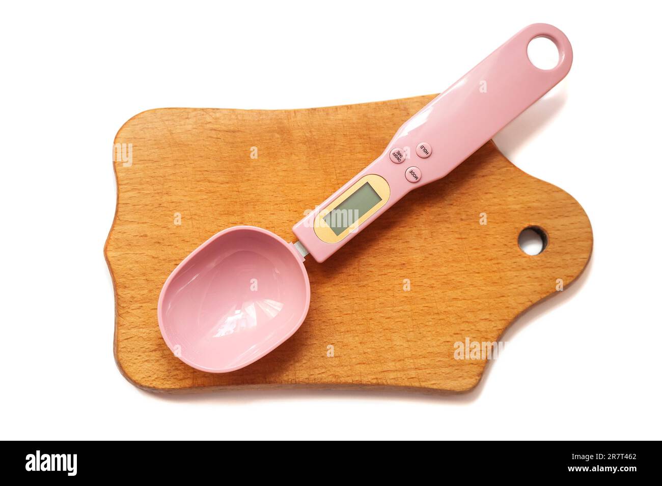 Un cucchiaio di misurazione elettronico di colore rosa si trova su un tagliere di legno. Sfondo bianco. Il concetto di alimentazione sana e di controllo del peso prodotto Foto Stock