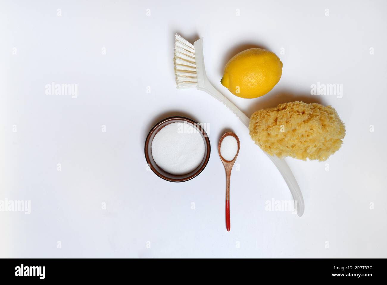 Acido citrico in cucchiaio di legno e ciotola piccola, spazzola per la pulizia, spugna e limone Foto Stock