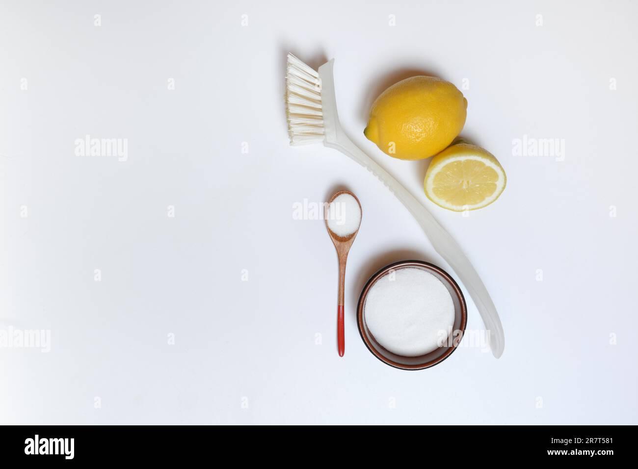 Acido citrico in cucchiaio di legno e ciotola piccola, spazzola per la pulizia e limone Foto Stock