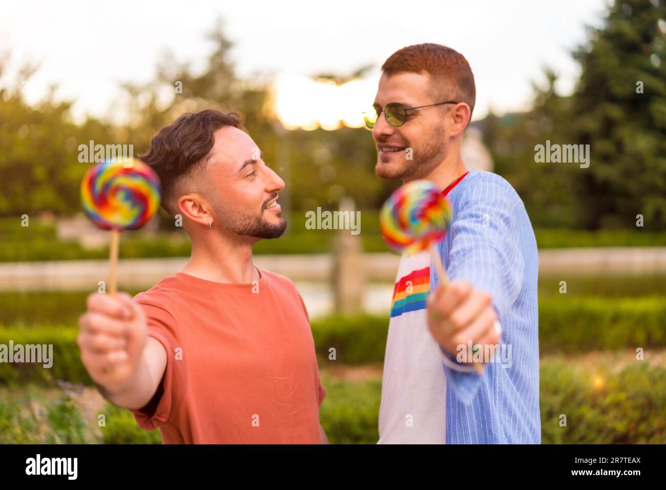 Ritratto di coppia gay matrimonio mangiare un lecca nel parco al tramonto in città. concetto lgbt Foto Stock