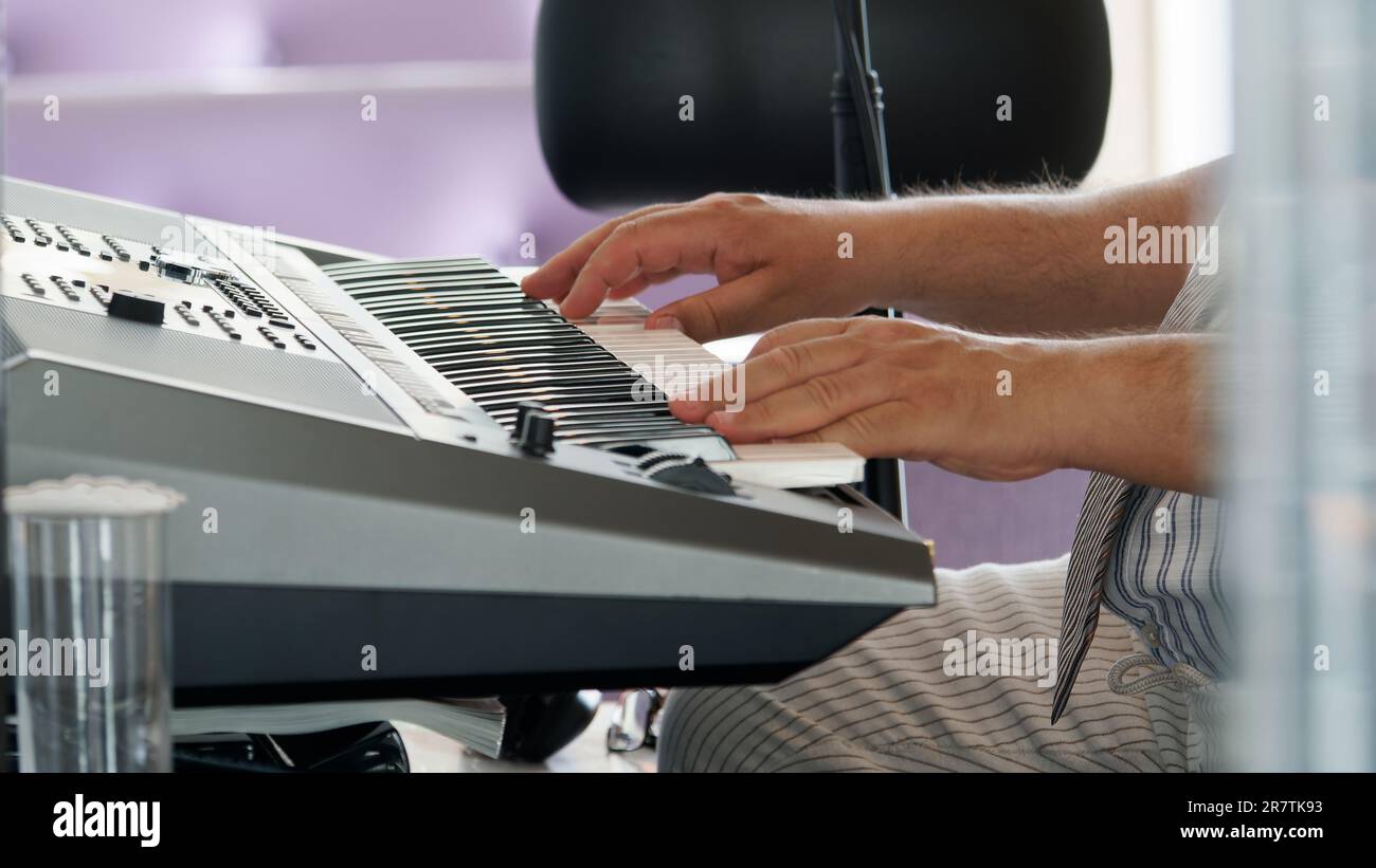 Musicista che suona il piano della tastiera in un ambiente luminoso interno Foto Stock