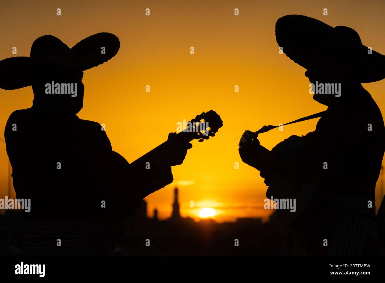 Silhouette di una band mariachi di musicisti messicani sullo sfondo del panorama della città. Foto Stock