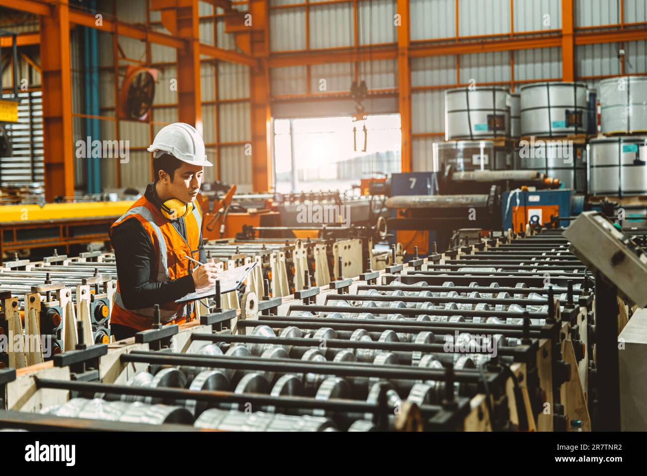 Giovane ingegnere tecnico supervisore che lavora QC in lamiera lavorazione controllo linea di produzione. Foto Stock