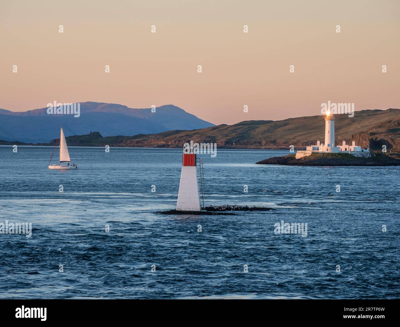 Faro di Lismore, mare tra Oban e Isola di Mull, tramonto, barca a vela singola, Scozia, Regno Unito Foto Stock