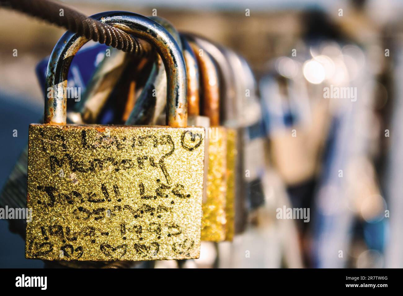 Un primo piano di una collezione di tre lucchetti con un messaggio d'amore scritto su uno di essi, fissato su una recinzione metallica Foto Stock