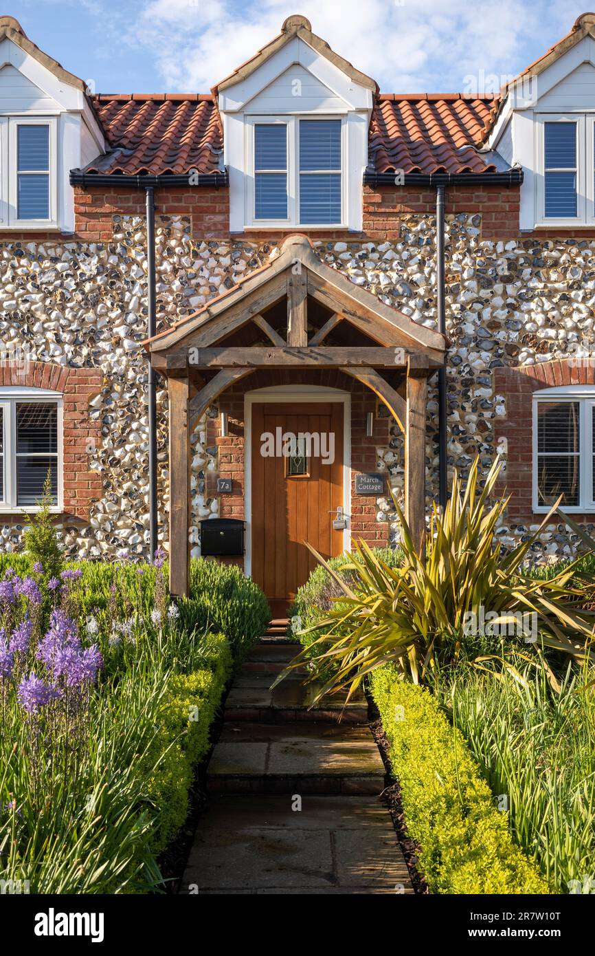 Tradizionale grazioso cottage in mattoni e selce con portico, finestre dormitorio, giardino anteriore e percorso nel pittoresco villaggio di Great Massingham a Norfolk, Inghilterra Foto Stock