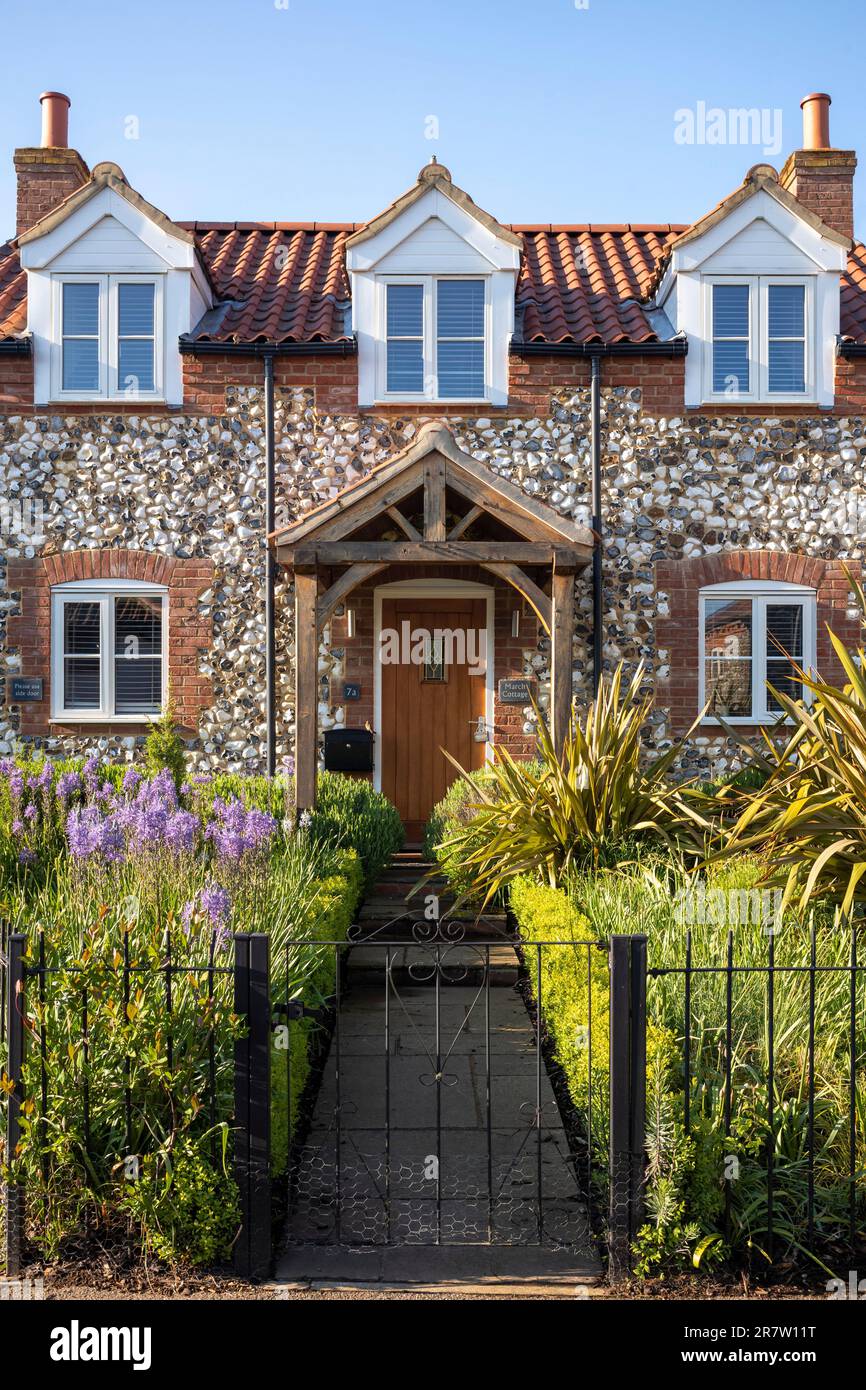 Tradizionale cottage in mattoni e selce con portico, finestre dormitorio, giardino anteriore, percorso e ringhiere nel pittoresco villaggio di Great Massingham a Norfolk, Engl Foto Stock