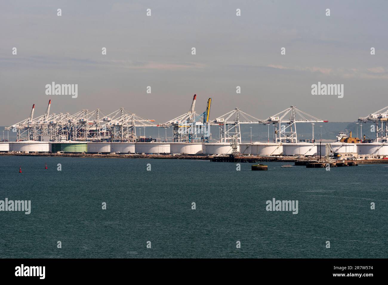 Le Havre, Francia settentrionale, Europa. 2023. Gru nel porto dei container e serbatoi di stoccaggio accanto a un molo nel porto di le Havre, Francia. Foto Stock