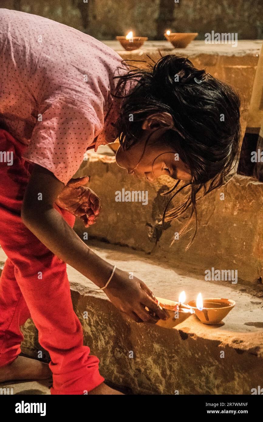 Un bambino accende lampade ad olio per celebrare Dev Deepawali sui Ghats di Varanasi, India Foto Stock
