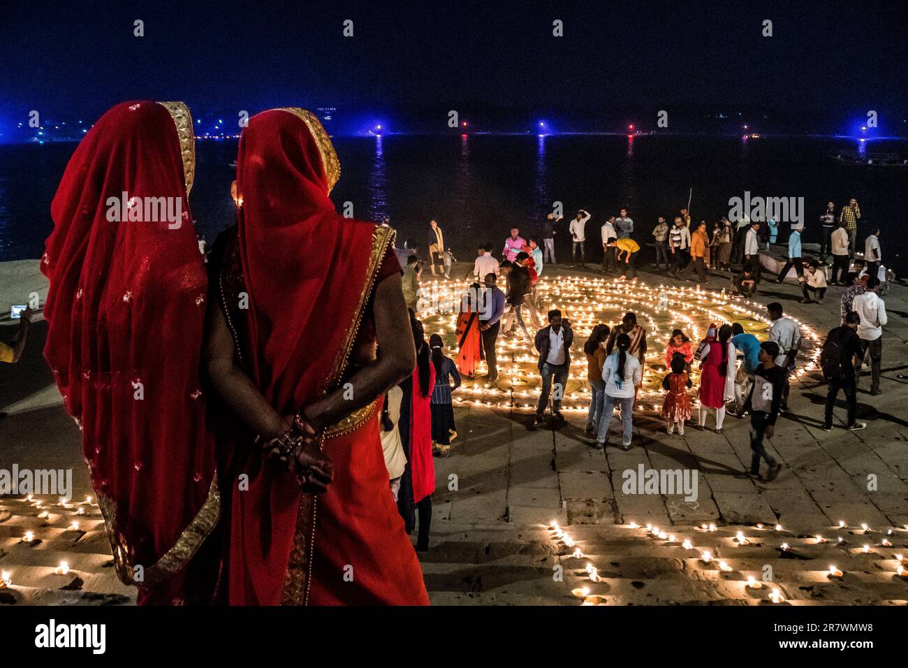 Le donne guardano fuori sopra le lampade del petrolio sui ghats di Varanasi durante le celebrazioni di Dev Deepawali in India Foto Stock