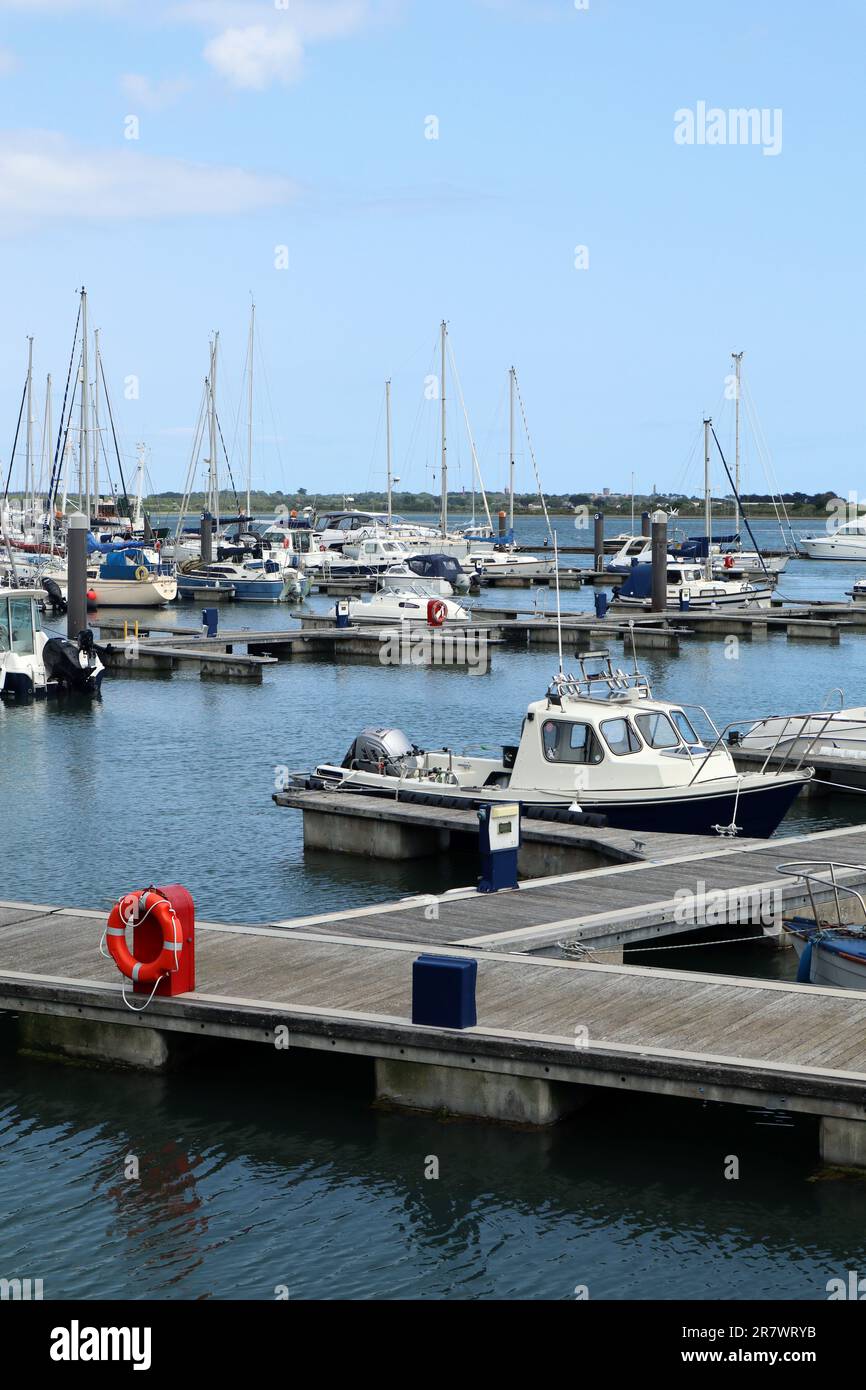 E' una giornata estiva di sole vicino al mare. Bellissimo porto yacht con una scialuppa di salvataggio rossa e un sentiero in legno. Acque cristalline e yacht da pesca. Foto Stock