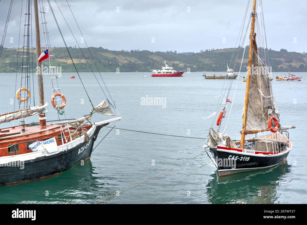 Barche da pesca e a vela ormeggiate al largo della costa dell'isola di Chiloe in Cile Foto Stock