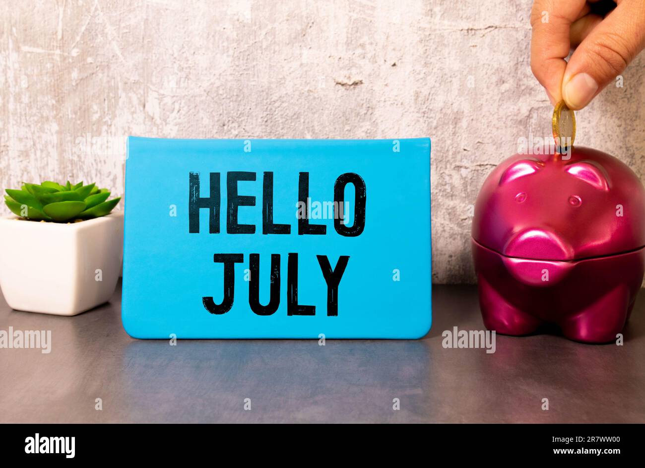 Foglio bianco di carta con l'iscrizione CIAO LUGLIO su uno sfondo giallo brillante vicino alla foglia verde della pianta. Eco naturale banner concetto Foto Stock