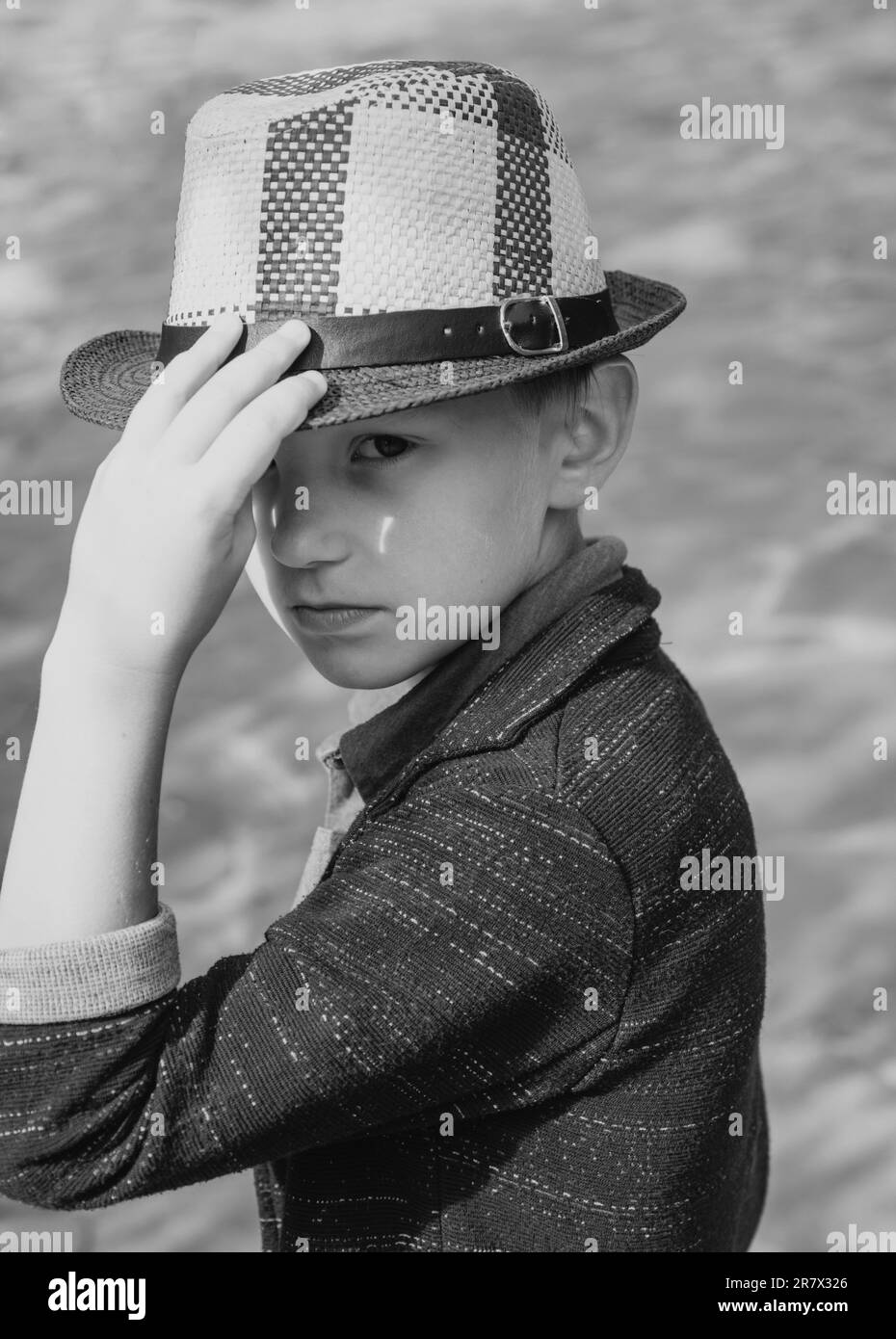 Ragazzo carino che gioca con le foglie e guarda la macchina fotografica. Il ragazzino si sta preparando per la vendita autunnale. Primo piano verticale Foto Stock