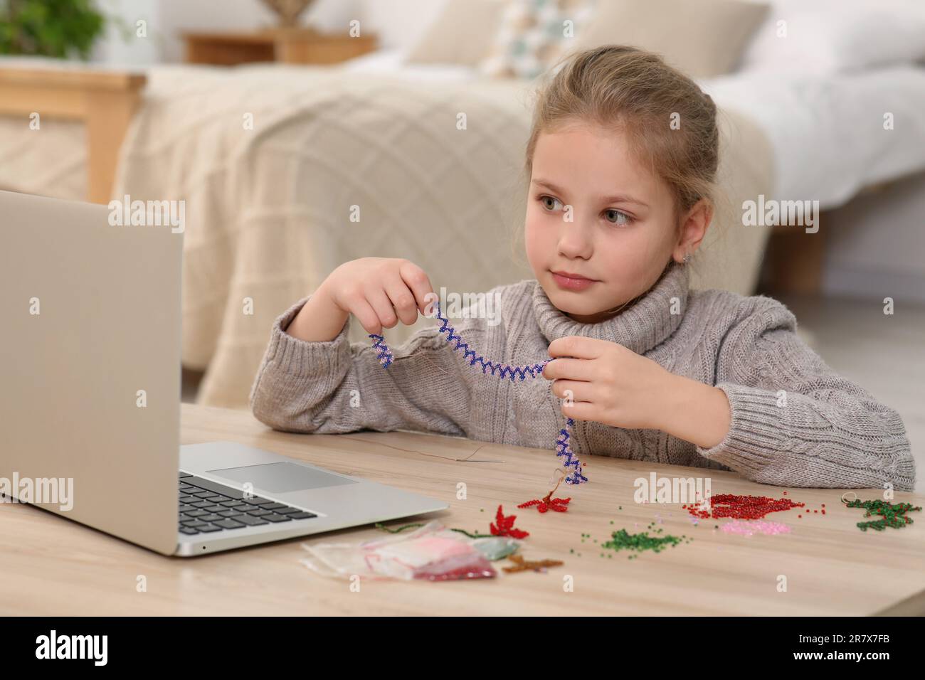 Bambina imparando a fare gioielli con perline con corso online a casa.  Tempo per hobby Foto stock - Alamy