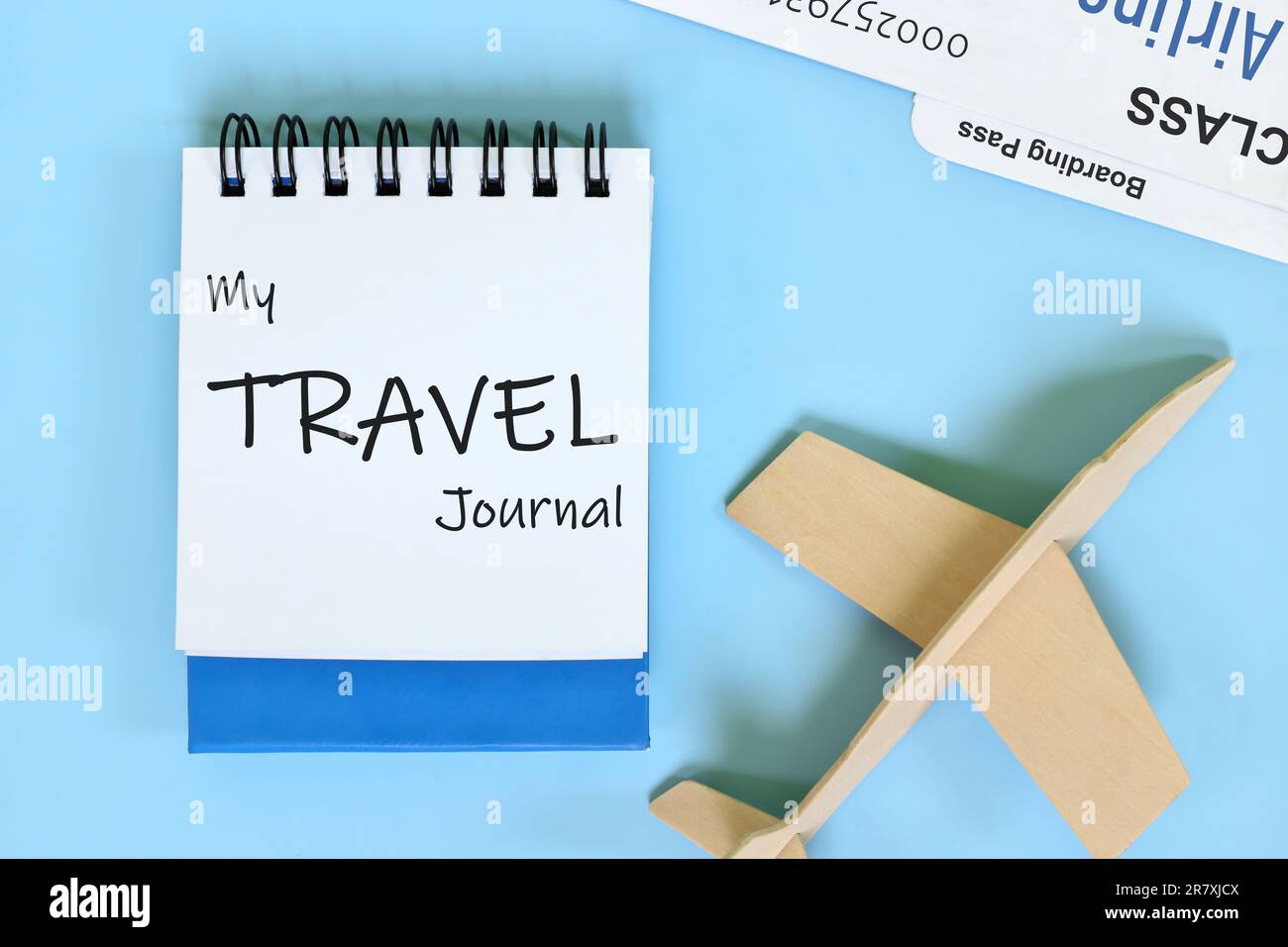 Composizione piatta diario di viaggio con aereo in legno e biglietto per la carta d'imbarco. Foto Stock