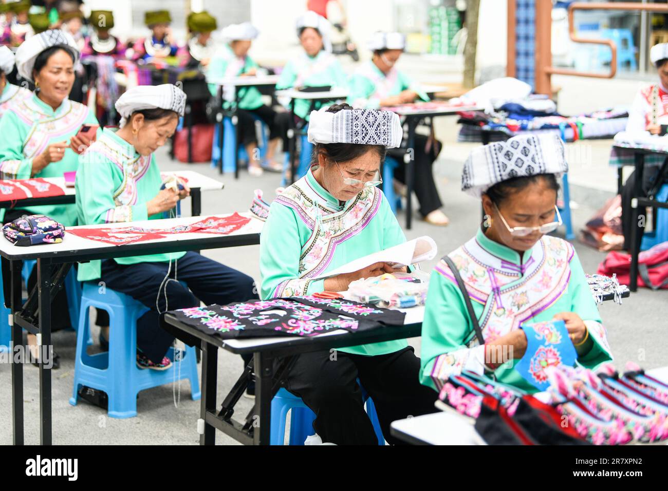 I ricamatori lavorano in un laboratorio a Qianxinan, provincia di Guizhou, Cina, 18 giugno 2023. Foto Stock