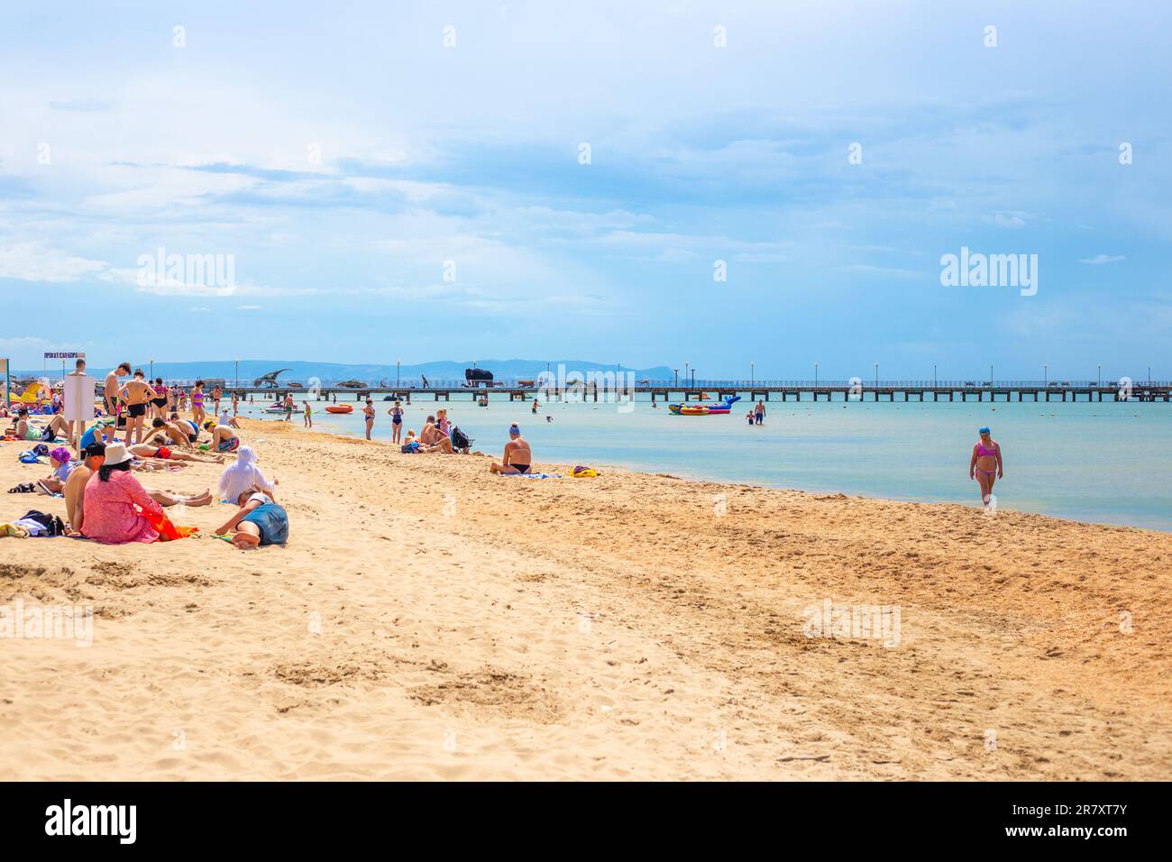 Vacanze al mare sulla costa. Spiaggia di sabbia con molo. Turisti vacanzieri sulla riva e sul mare. Russia, Vityazevo-04.06.2023 Foto Stock