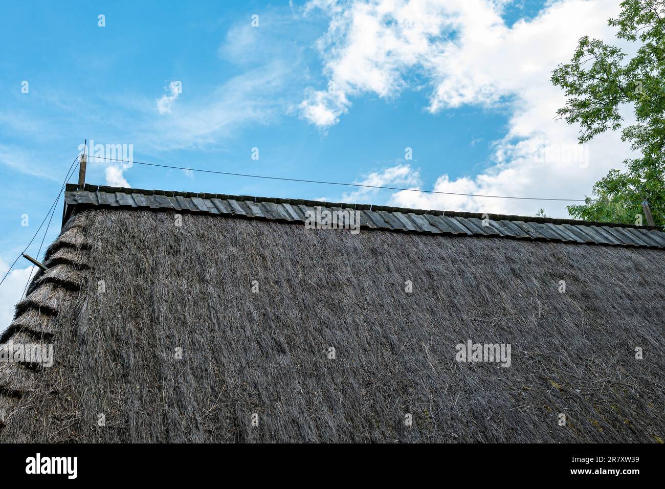Tetto di paglia contro il cielo blu. Protezione dai fulmini. La cresta è coperta da tavole di legno Foto Stock