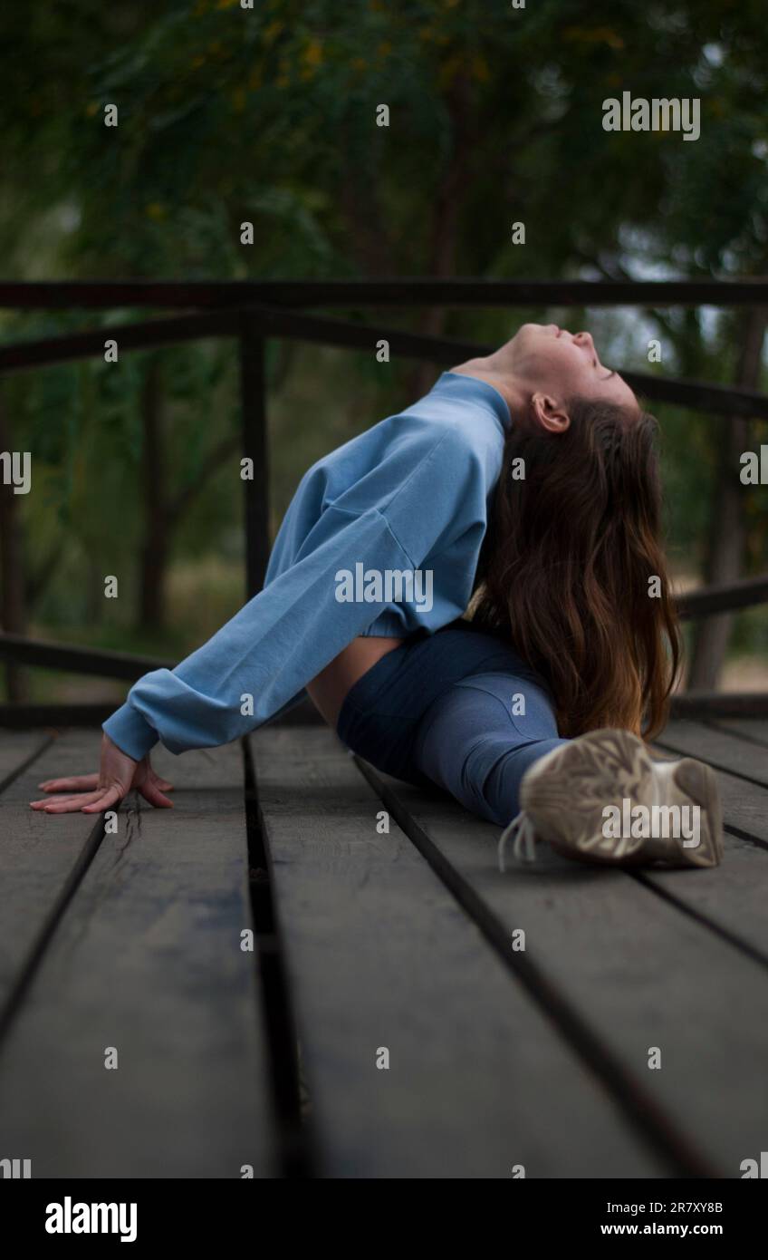 Vista di una ragazza sta facendo split nel parco in tempo nuvoloso Foto Stock