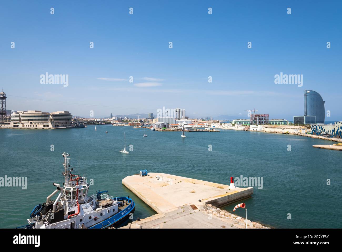 Vista sul bacino del porto di Barcellona con il World Trade Center di Barcellona e il famoso porto turistico Port Vell. In primo piano è ormeggiata una barca a rimorchiatore. Acceso Foto Stock