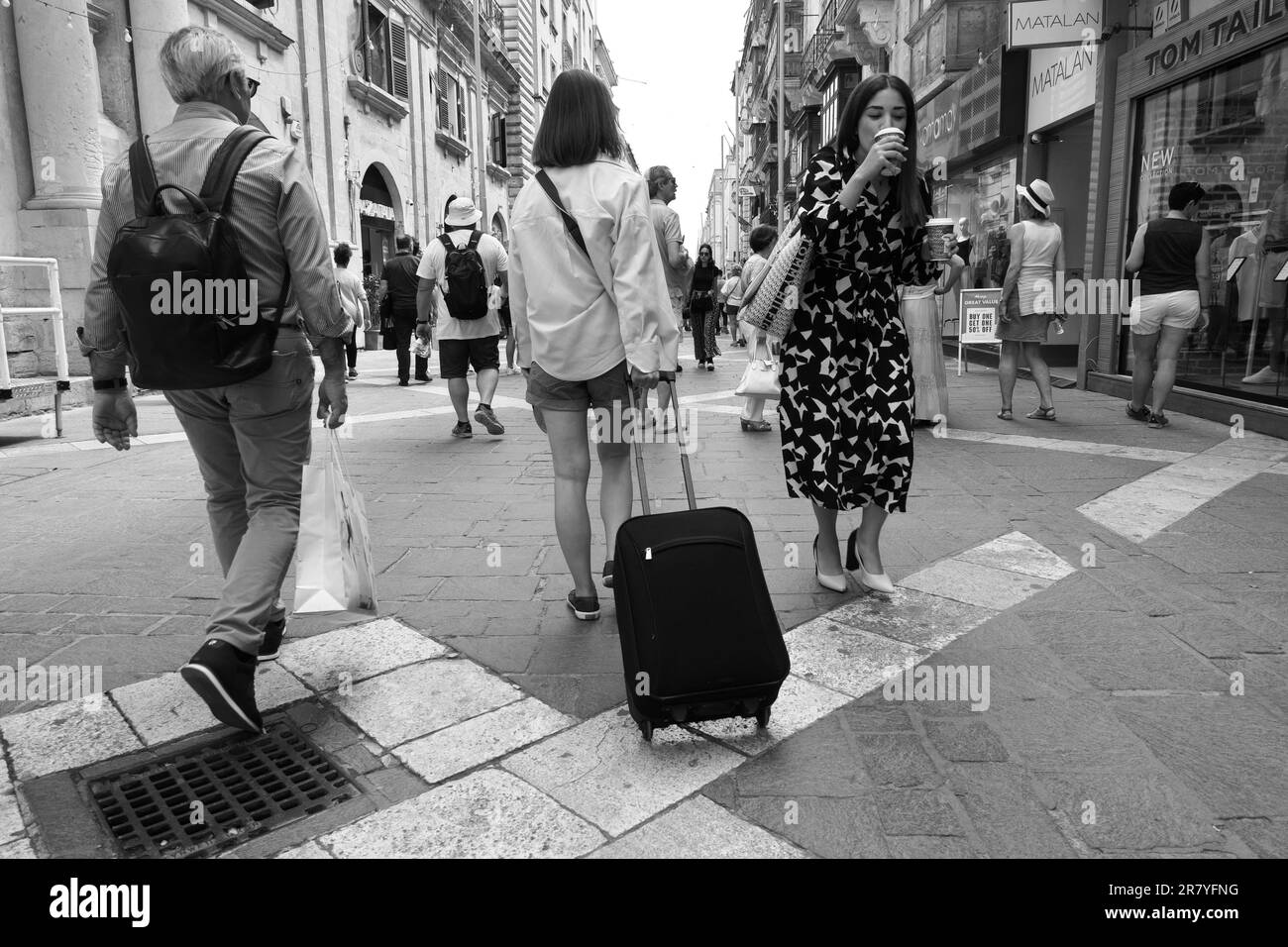 Fotografia in bianco e nero dei turisti con zaino o carrello in Republic Street di Valletta, Malta Foto Stock