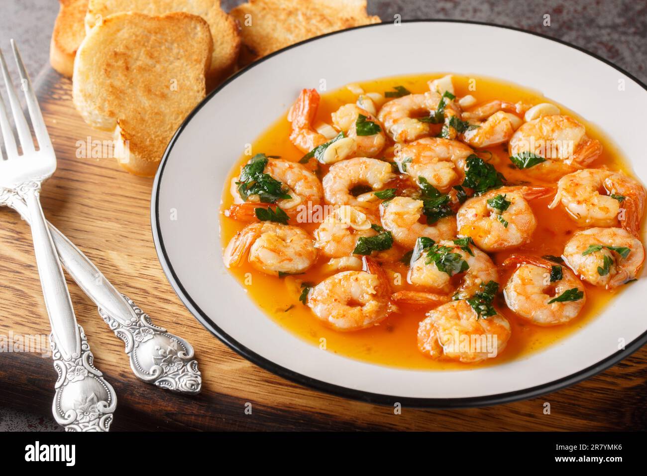 Gambas al ajillo o gamberi all'aglio è una tradizionale tapas spagnola fatta combinando gamberi freschi con una salsa ajillo sul bordo di legno. Orizzontale Foto Stock