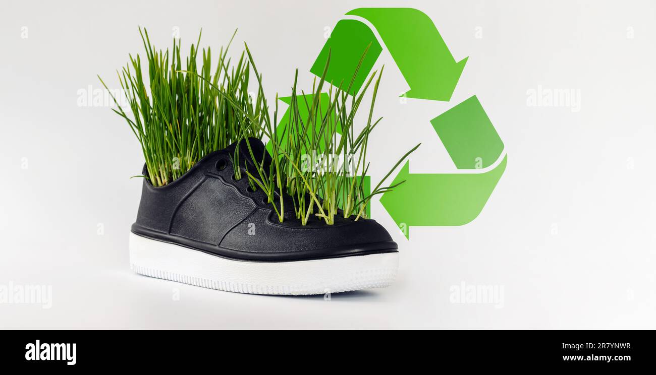 Concetto di conservazione dell'ambiente, riciclaggio e riutilizzo, erba verde proveniente da scarpe in gomma. Foto Stock
