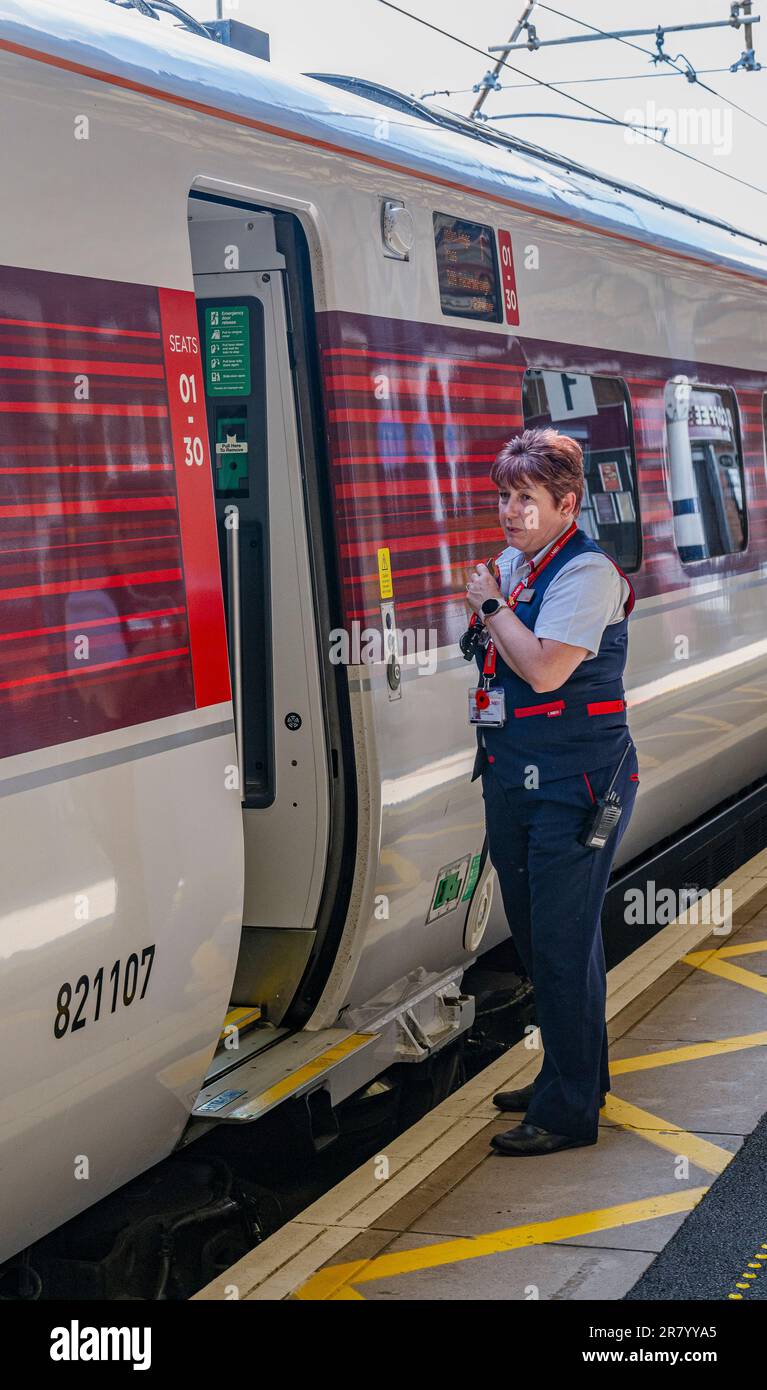 Grantham Train Station – Una direttrice o guardia femminile che spedisce un treno Azuma London North Eastern (LNER) dalla piattaforma Foto Stock