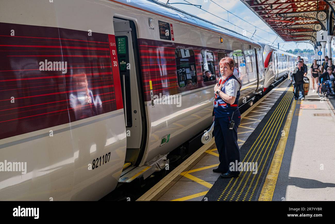 Grantham Train Station – Una direttrice o guardia femminile che spedisce un treno Azuma London North Eastern (LNER) dalla piattaforma Foto Stock