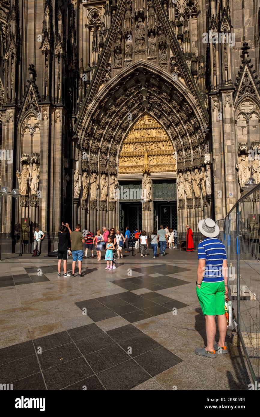 Uomo con pantaloncini Bermuda verdi e cappello di fronte all'ingresso della cattedrale di Colonia, Germania. Mann mit gruenen Bermudashorts und Hut steht Foto Stock