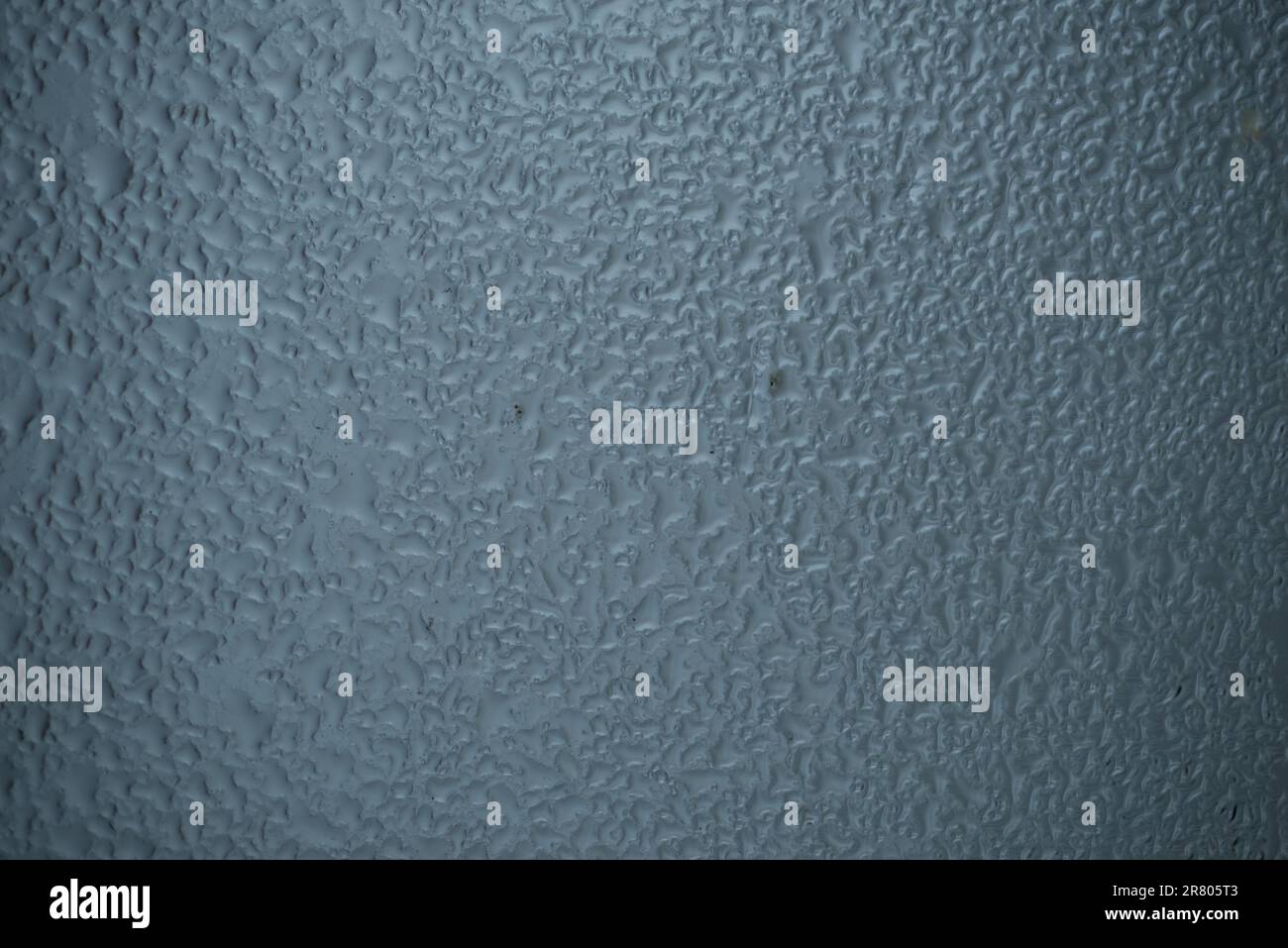 Gocce di pioggia sul vetro della finestra su sfondo grigio sfocato Foto Stock