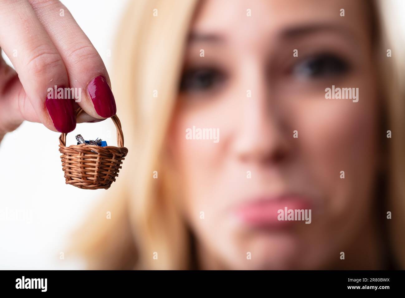 Microscopico presente in piccolo cestino tenuto da blurry, donna molto triste. Il regalo è al di sotto delle sue aspettative Foto Stock