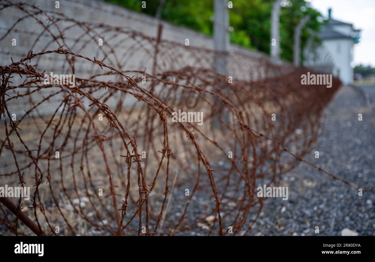 Oranienburg, Germania. 18th giugno, 2023. Il filo spinato arrugginito giace a terra contro un muro sul terreno dell'ex campo di concentramento di Sachsenhausen. Nel giugno del 1938, gli agenti di polizia criminali hanno deportato più di 10.000 persone nei campi di concentramento, dove sono state segnate con un angolo nero. La campagna di arresto a livello nazionale è stata diretta contro persone che sono state etichettate 'asocial? Dai socialisti nazionali. Tra di loro c'erano senzatetto, alcolisti e persone con un record criminale per, tra l'altro, l'elemosina. Credit: Monika Skolimowska/dpa/Alamy Live News Foto Stock